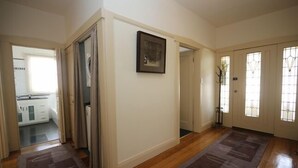A hallway with wooden flooring, white walls, and a door leading to a kitchen.