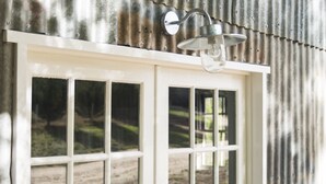 Une fenêtre à cadre blanc, avec un extérieur en métal et un luminaire suspendu.