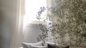 Un canapé blanc avec un coussin noir et un petit arrangement floral blanc.