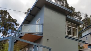 A two-story house with a balcony and wooden steps leading to a deck.
