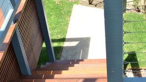 A wooden deck with metal railings and a concrete pathway.