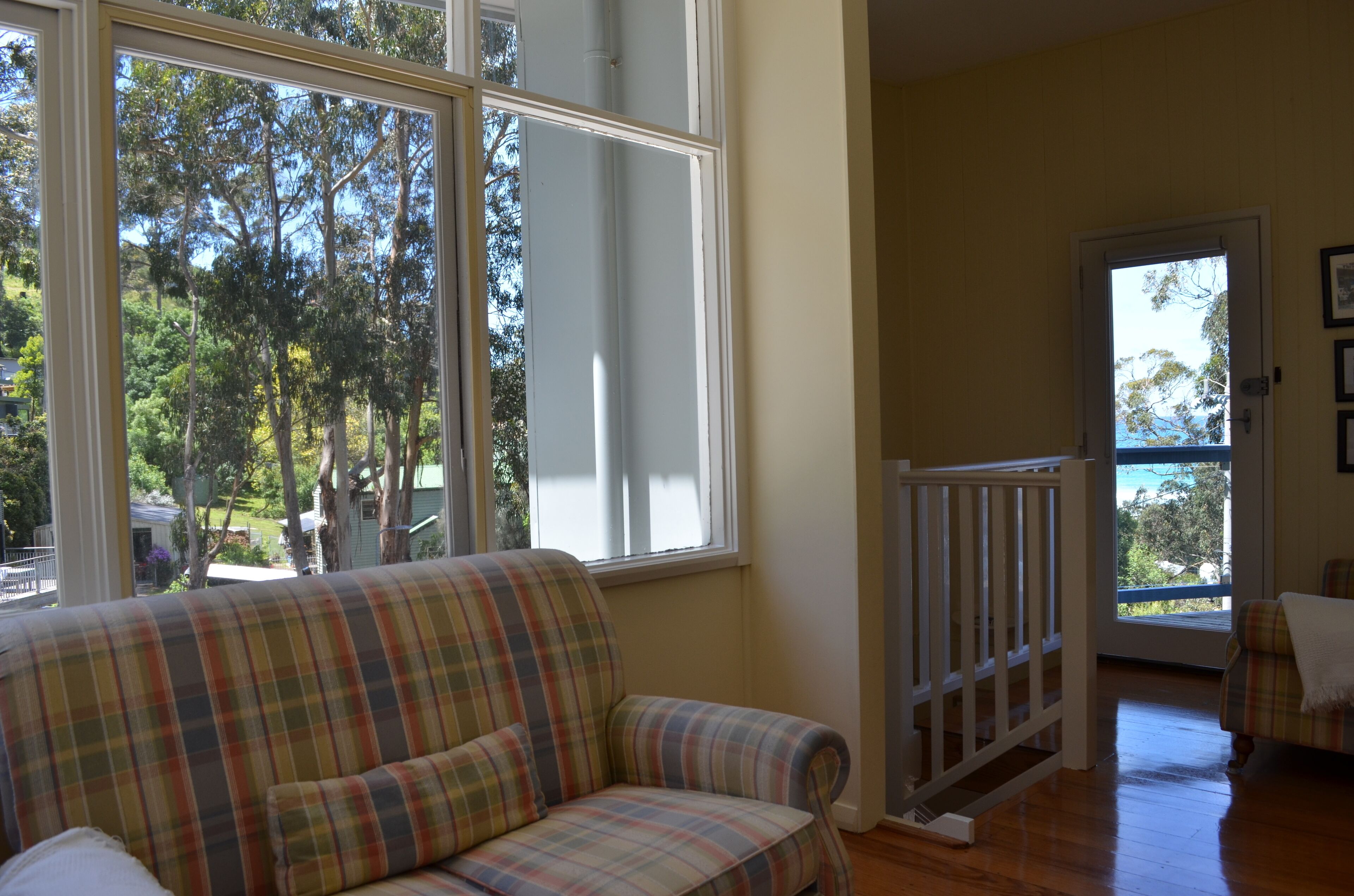 A room with a plaid sofa, a wooden floor, and a door leading outside.