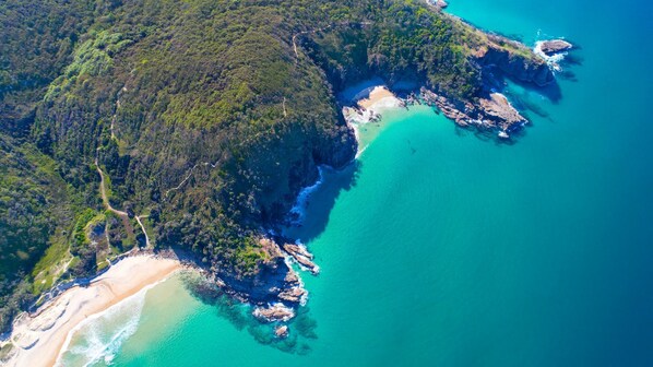 An aerial view of a coastal area with a beach, dense forest, and clear blue waters. - Domani - Large Townhouse with Ocean Views (Sunshine Beach)