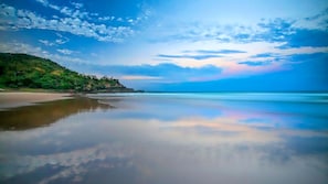 A beach with a calm sea, clear sky, and a forested hillside. - Domani - Large Townhouse with Ocean Views (Sunshine Beach)