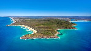 An aerial view of a coastal area with a large beach, clear blue waters, and a dense forested island. - Domani - Large Townhouse with Ocean Views (Sunshine Beach)