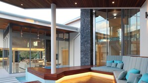 Un intérieur moderne avec une terrasse en bois, un mur d’accent en pierre et un canapé à rayures agrémenté de coussins.