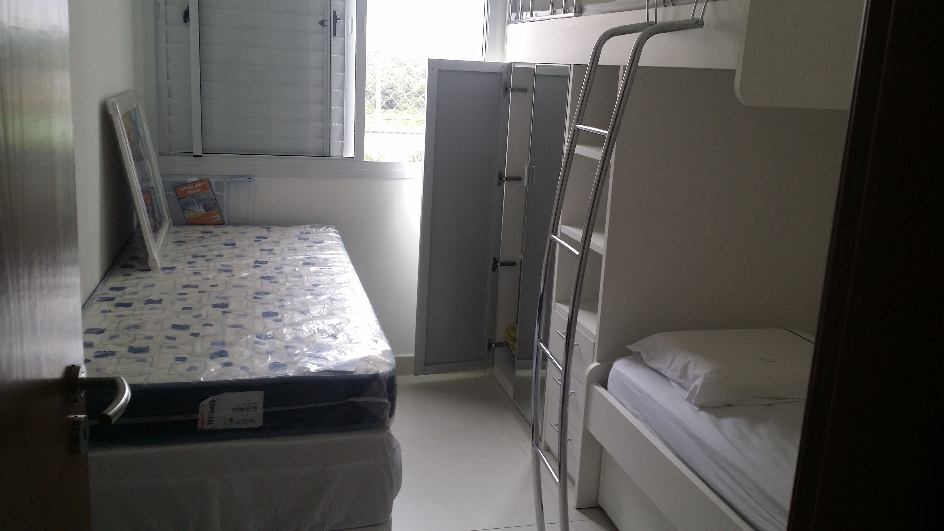 A compact room with a bunk bed, a small window, and a door.