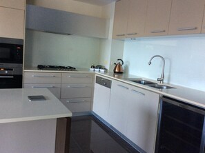 A modern kitchen with stainless steel appliances, a dishwasher, and a kettle.