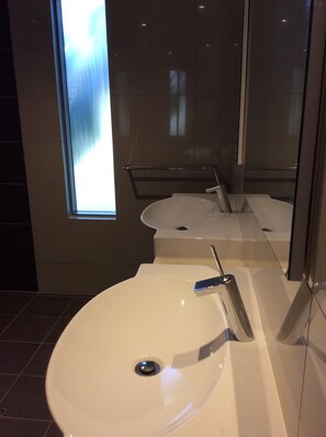 A modern bathroom with a large white sink, a bathtub, and a glass shower enclosure.
