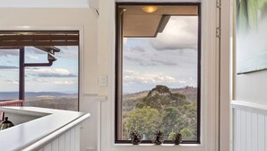 A room with a large window offering a scenic view of a forested mountain range. - Quingilli Luxury Chalet 3 Bedrooms (Ravensbourne)
