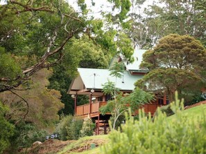 A two-story house with a green roof, surrounded by dense greenery and trees. - Quingilli Luxury Chalet 3 Bedrooms (Ravensbourne)