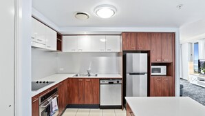 A modern kitchen with white cabinets, stainless steel appliances, and wooden accents. - Apartment 2196 offers the perfect holiday adobe for small families and couples (Surfers Paradise)