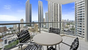 A balcony with a round table and two chairs, overlooking a cityscape with tall buildings and a view of the ocean. - Apartment 2196 offers the perfect holiday adobe for small families and couples (Surfers Paradise)