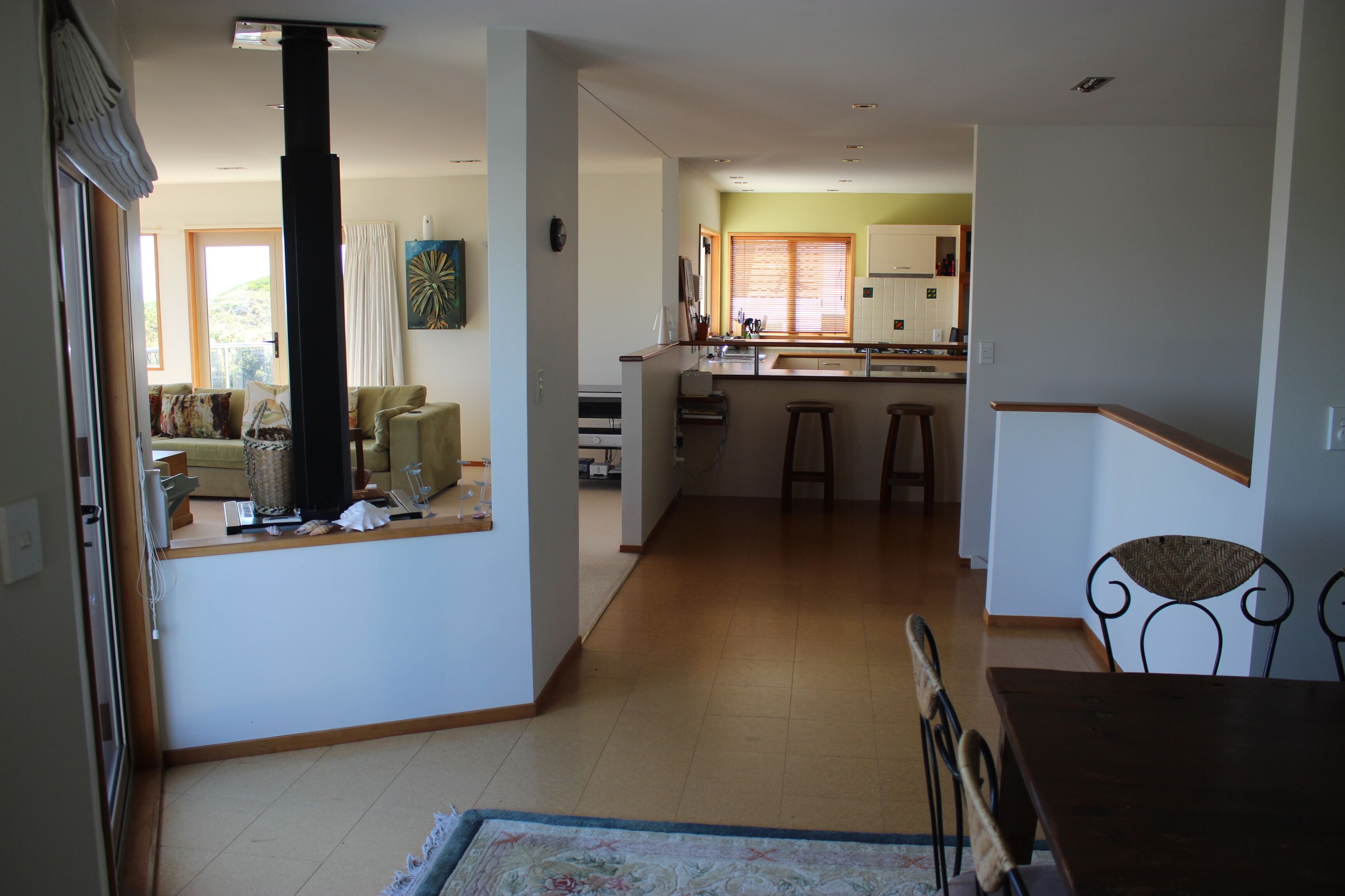 A spacious living area with a kitchen in the background, a large window, and a wooden dining table.