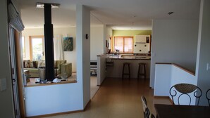 Ein geräumiger Wohnbereich mit einer Küche im Hintergrund, einem großen Fenster und einem Holzessttisch.