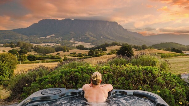 Une personne se détend dans un bain à remous, avec un paysage montagneux en arrière-plan.
