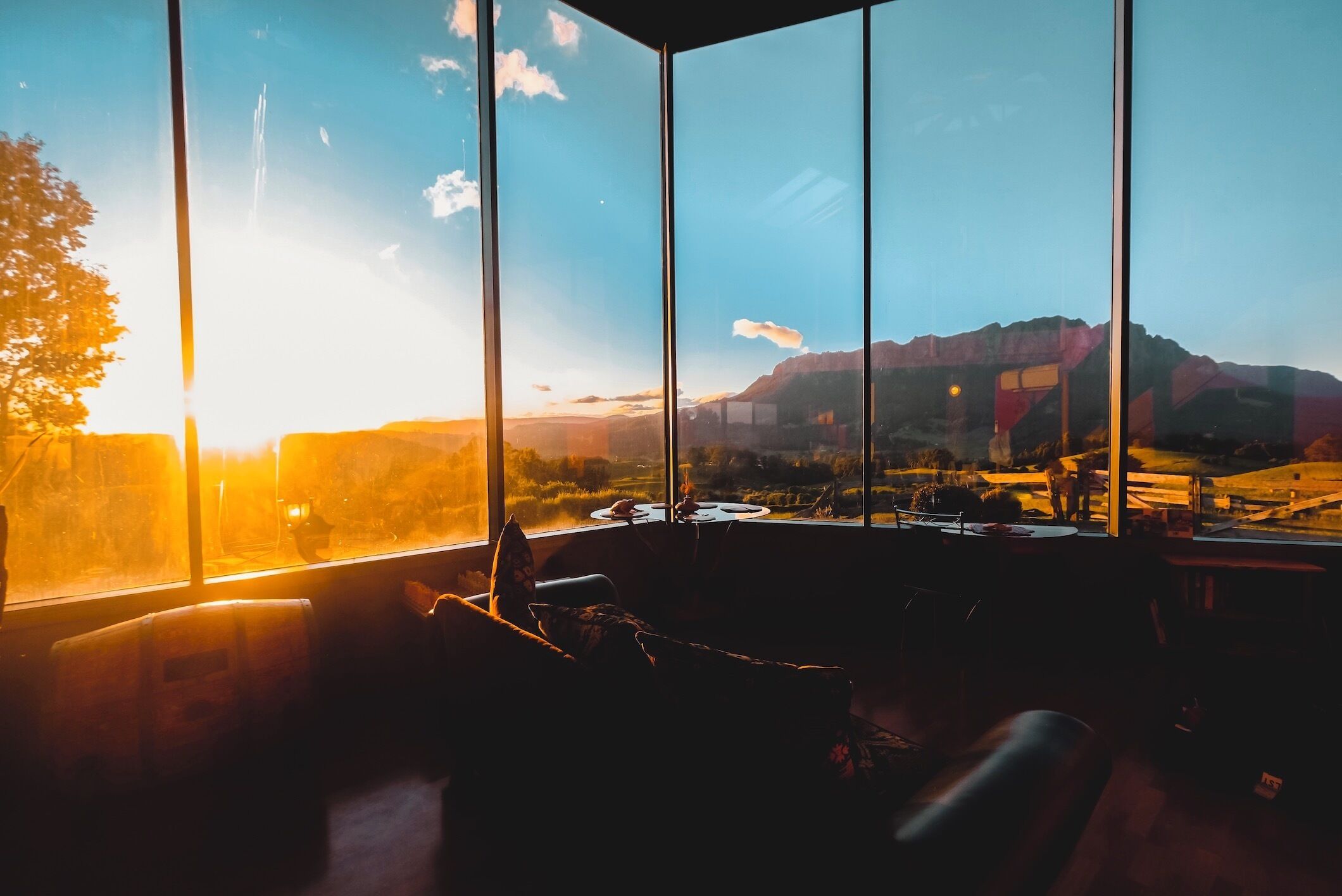 A room with large windows, a sofa, and a table.