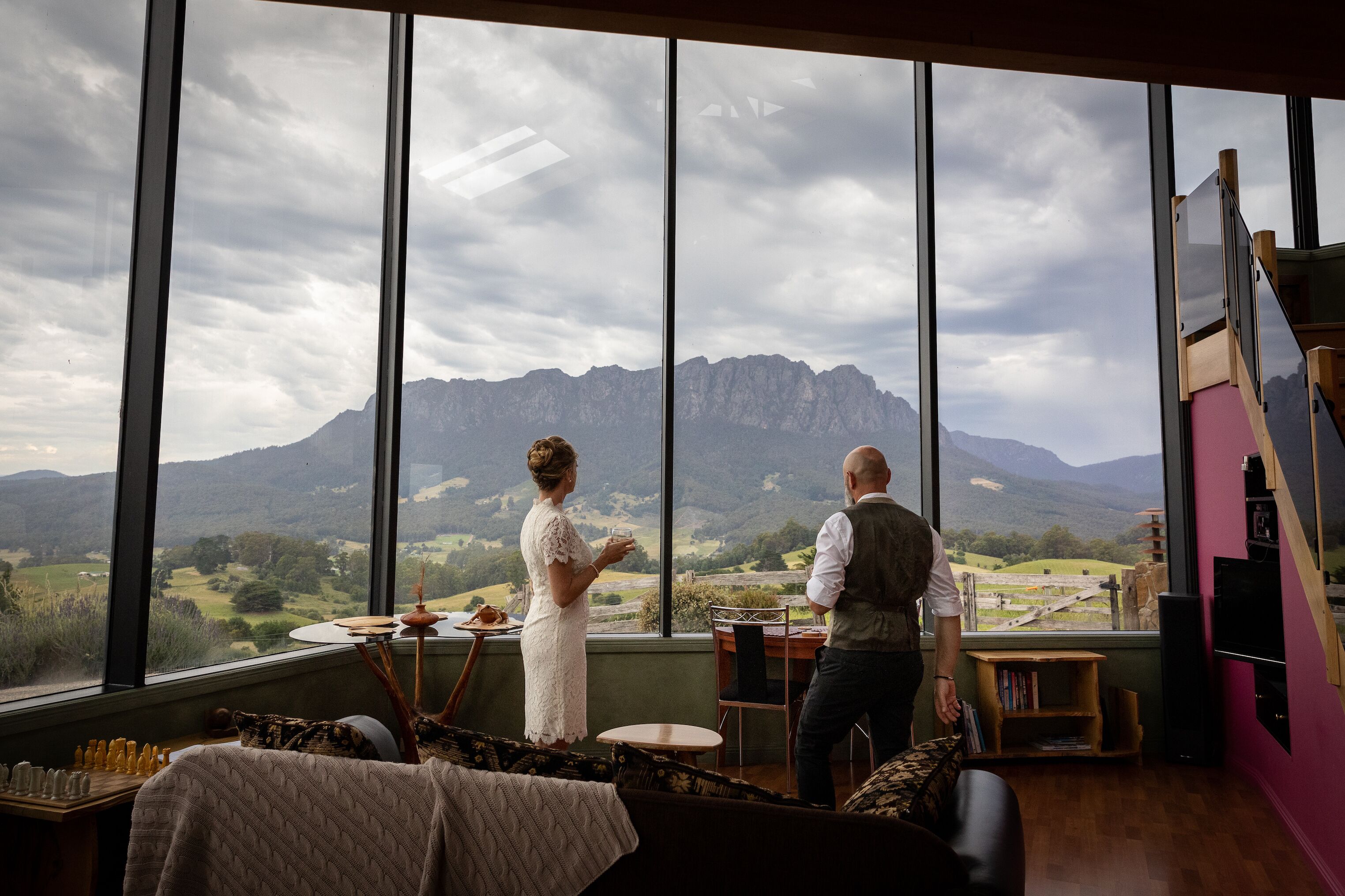 A room with large windows offering a mountain view, a dining area with a table and chairs, and a cozy seating area with a patterned rug.