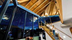 Un intérieur moderne avec un plafond en bois, de grandes fenêtres et un escalier.