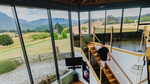 Un intérieur moderne avec une grande fenêtre, un escalier en bois et un coin salon.