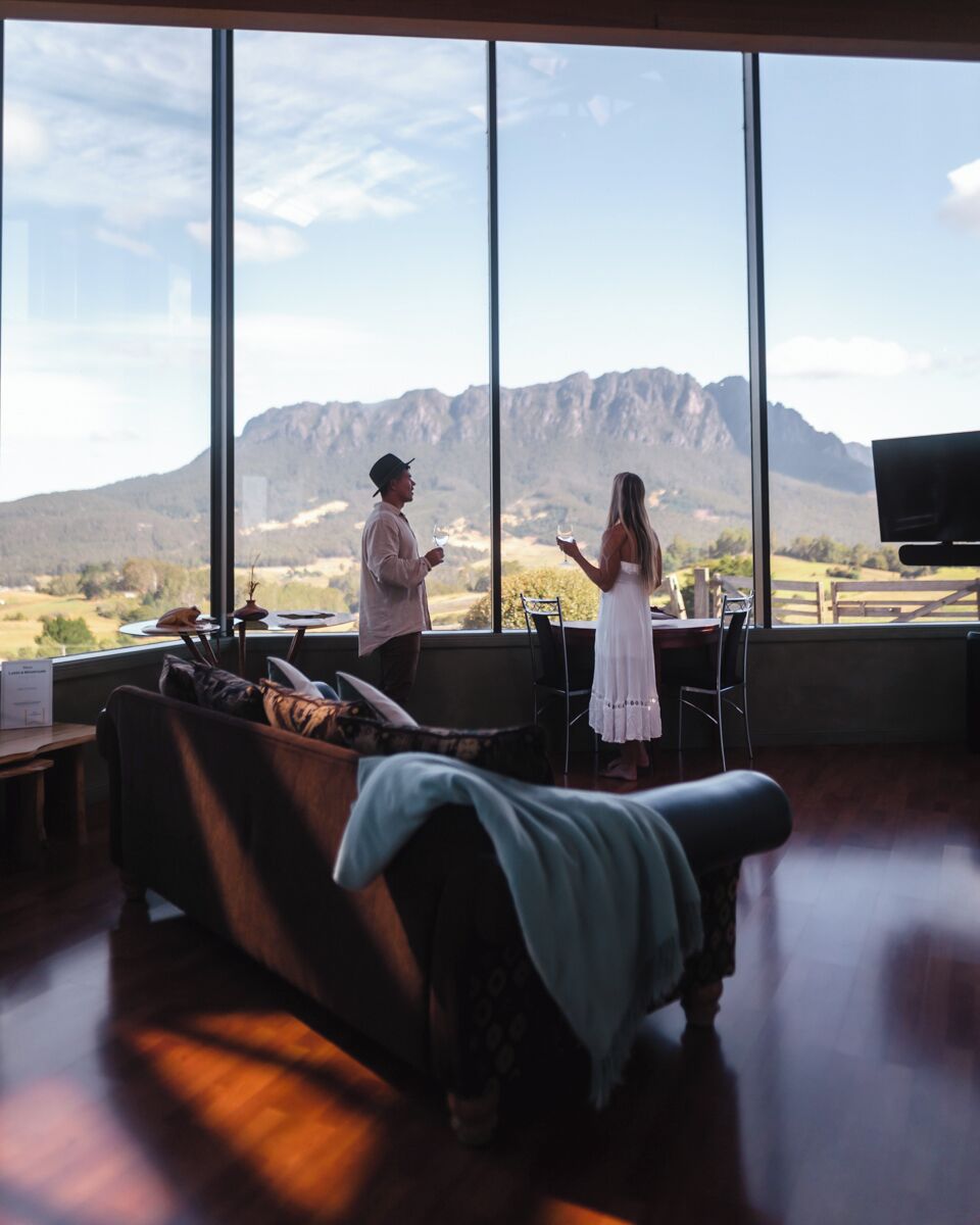 Una habitación con un ventanal grande que ofrece vistas a un paisaje montañoso, un sofá y una mesa de comedor.