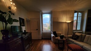 Una sala de estar acogedora con suelo de madera, un sofá, una mesa de centro y un televisor sobre un mueble de madera.