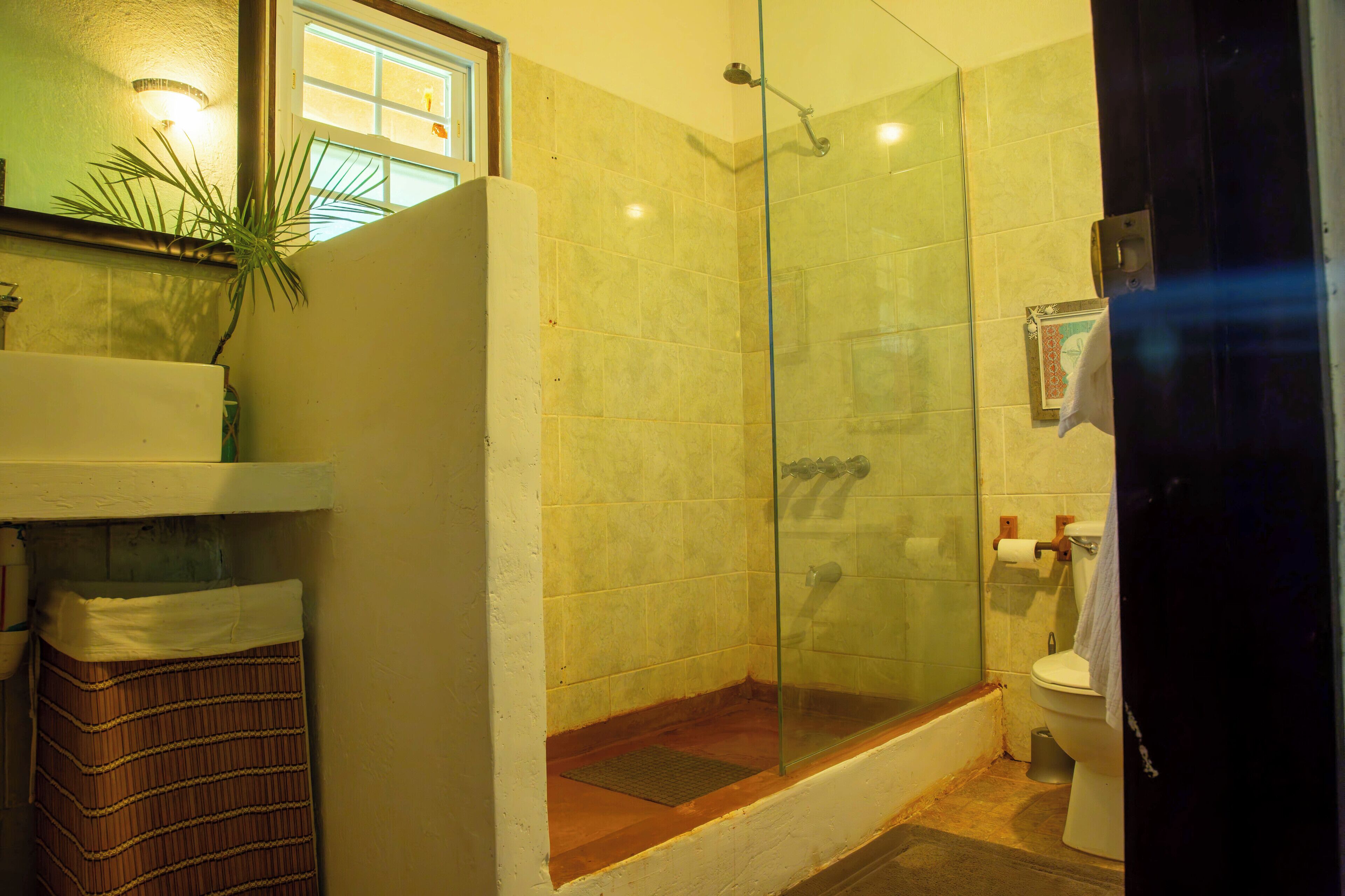 Un bagno con doccia vetro, servizi igienici e lavandino.