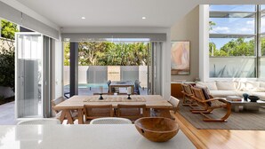 Um espaço de estar moderno e integrado, com área de jantar, piscina e um local para sentar com vista para o exterior.