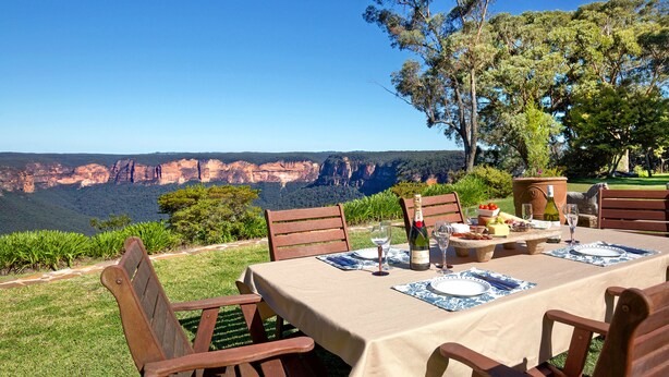 Een eethoek buiten met een tafel gedekt voor vier personen, met uitzicht op een canyon.