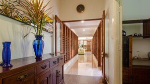 A hallway with a wooden cabinet, a blue vase, and a plant.