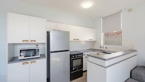 A compact kitchen with a refrigerator, microwave, stove, oven, and a sink. - HEADLANDS 2: 2  BR, 1  BA Apartment in Port Macquarie, Sleeps 4 (Port Macquarie)