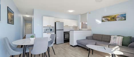 A modern apartment with a dining area, kitchen, and living space.