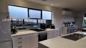 Eine moderne Küche mit weißen Schränken, einem eingebauten Backofen, einer Kaffeemaschine und einem großen Fenster mit Blick auf die Landschaft.