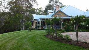 Une maison avec un toit bleu, une pelouse bien entretenue et un jardin où poussent différentes plantes et fleurs.