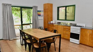 A kitchen with a wooden table and chairs, a stove, and cabinets. - Tuteveras' Arms - Arorangi (Arorangi)