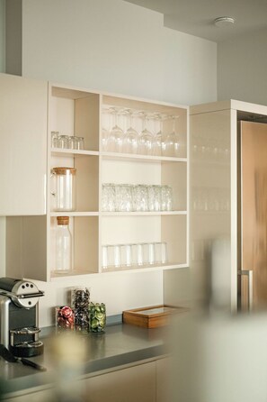 A kitchen with white cabinets, a coffee machine, and a wooden countertop.