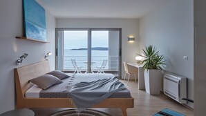 A modern bedroom with a large bed, a desk, and a view of the sea. - A Place Where The Garden Ends And The Sea Begins (Milna)