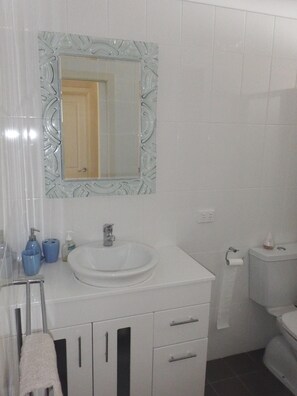 A bathroom with a white sink, a mirror with a decorative frame, a toilet, and a towel rack. - Lampe House - A cosy, pet friendly cottage at Talbingo, Snowy Mountains NSW (Talbingo)