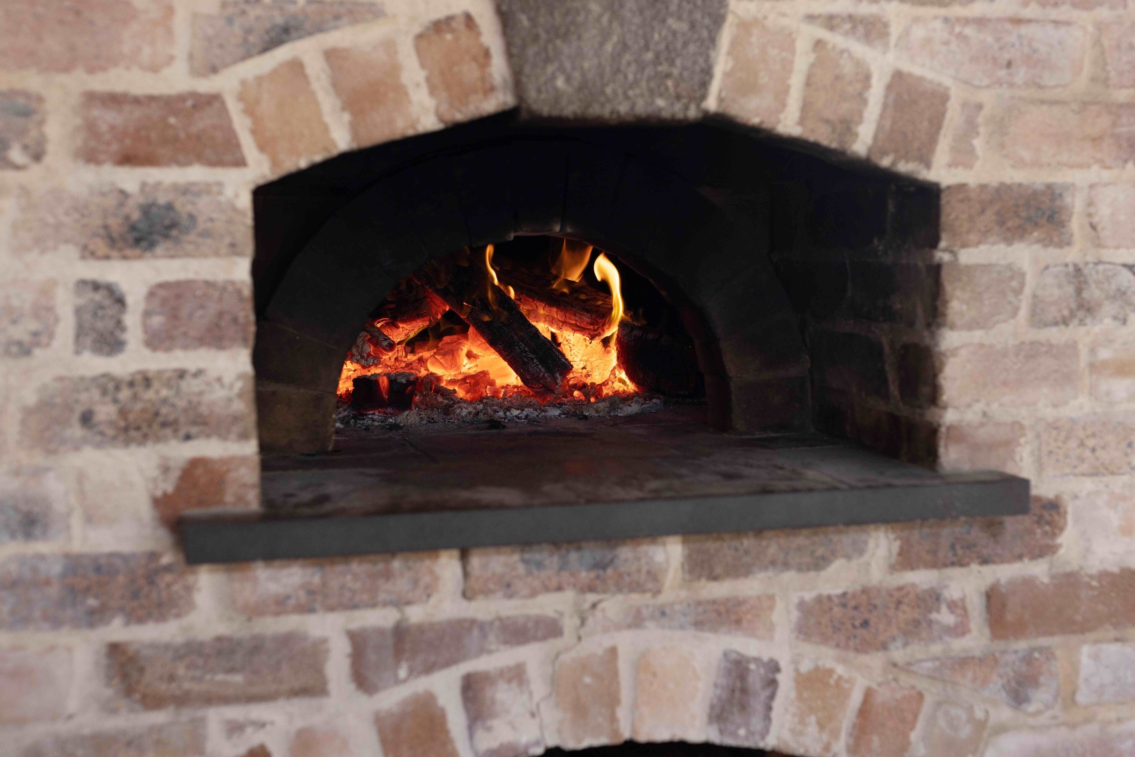 A brick fireplace with a fire burning inside.