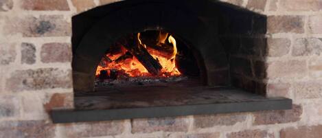 A brick fireplace with a fire burning inside.
