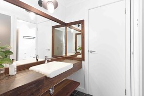 A bathroom with a wooden vanity, a white sink, and a large mirror.