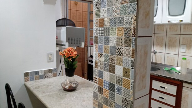 Una cocina con salpicadero de azulejos, encimera, lavabo y un armario.