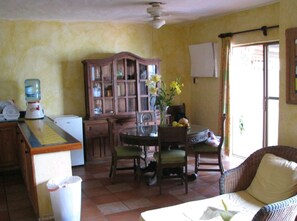 A dining area with a wooden table and chairs, a cabinet, and a water dispenser.