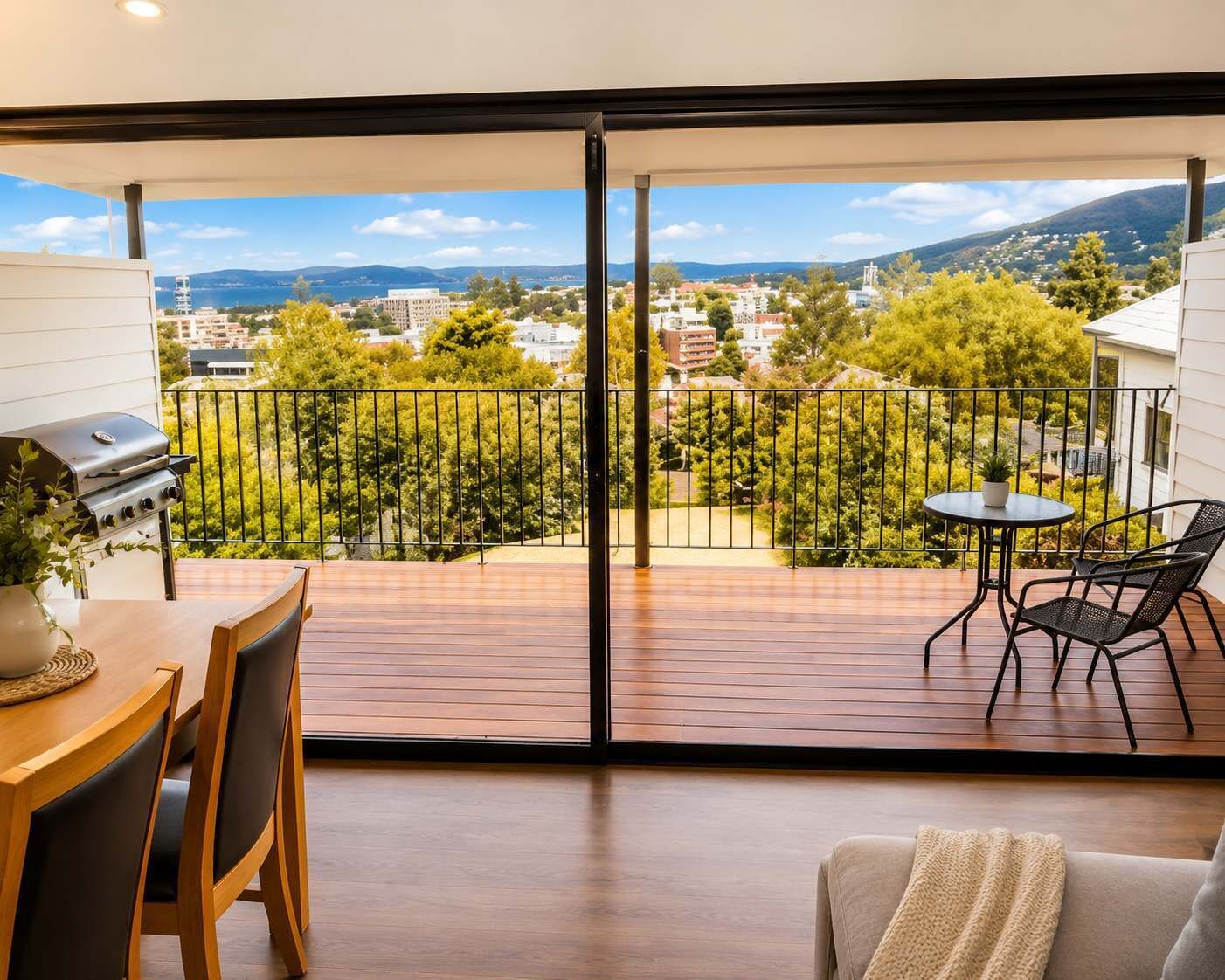Un balcón con vistas a un paisaje urbano, una parrilla y una mesa con sillas.
