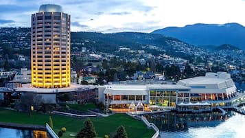 A high-rise hotel with multiple floors, a waterfront view, and a modern building complex with large windows and outdoor seating areas.