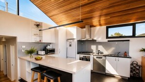 Una cucina moderna con isola centrale, elettrodomestici integrati e soffitto in legno.