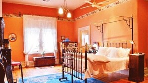 Ein Schlafzimmer mit einem Himmelbett, einem Deckenventilator und einem blauen Teppich mit Muster.