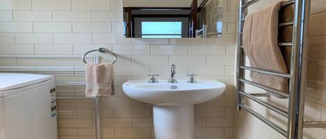 A bathroom with a white sink, a towel rack, a mirror, and a tiled floor.
