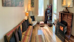 Una sala de estar acogedora con sofá, sillón, reposapiés y chimenea.