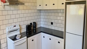 Una cocina compacta con alacenas blancas, estufa, microondas y refrigerador.